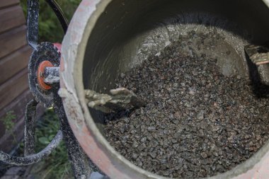 Açık hava inşaat alanında çakıl ve havan ile çimento karıştırıcısına yakın çekim. İnşaat malzemeleri, yenileme çalışmaları, inşaat mühendisliği ve somut hazırlık kavramı.