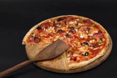 Tahta tahtada erimiş peynir, sosis, zeytin, biber ve soğanlı taze pizza yakın çekim. Restoran menüsü, fast food reklamı, İtalyan mutfağı ve teslimat konsepti için mükemmel..