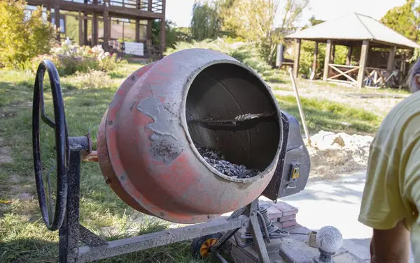 Açık hava inşaat alanında çakıl ve havan ile çimento karıştırıcısına yakın çekim. İnşaat malzemeleri, yenileme çalışmaları, inşaat mühendisliği ve somut hazırlık kavramı.