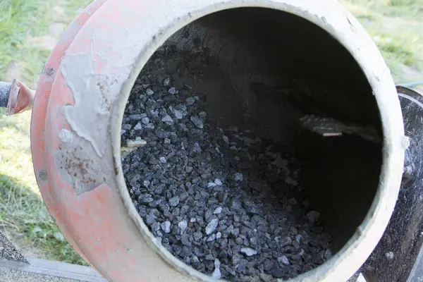 Açık hava inşaat alanında çakıl ve havan ile çimento karıştırıcısına yakın çekim. İnşaat malzemeleri, yenileme çalışmaları, inşaat mühendisliği ve somut hazırlık kavramı.