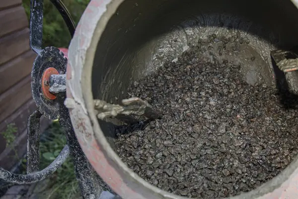 Açık hava inşaat alanında çakıl ve havan ile çimento karıştırıcısına yakın çekim. İnşaat malzemeleri, yenileme çalışmaları, inşaat mühendisliği ve somut hazırlık kavramı.