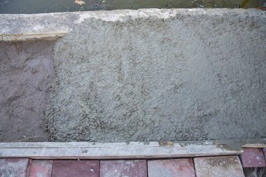 Forwork 'un içindeki kum tabanına çakıl taşlarıyla taze betonu kapatın. İnşaat, yol çalışması, inşaat malzemeleri ve vakıf hazırlığı kavramı