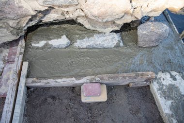 Forwork 'un içindeki kum tabanına çakıl taşlarıyla taze betonu kapatın. İnşaat, yol çalışması, inşaat malzemeleri ve vakıf hazırlığı kavramı