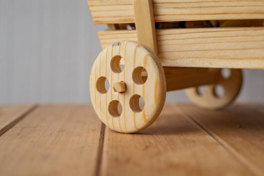 Close up of wooden wheel from a handmade toy cart on a wooden surface. Rustic design, eco friendly craftsmanship, natural material, and traditional decoration concept.