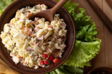 Sebzeli ev yapımı Olivier salatası yumurta ve mayonez kahverengi kâsede marul yaprakları ve ekmek çubuklarıyla servis edilir. Yemek fotoğrafçılığı ve yemek pişirmek için doğal arka plan.