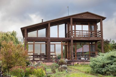 Modern wooden house with large windows and terrace located in green garden. Concept of sustainable architecture and eco living in countryside.