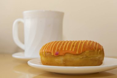 Portakal kremalı çörek ve masada beyaz bardak. Kafe ya da kafeterya için tatlı..