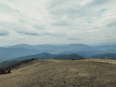 Dirt road, footpath at the top of the peak. Summer mountain landscape in calm beige colors. Carpathian Mountines, Ukraine, Eastern Europe. Mountain ranges on the horizon.