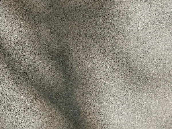 Plaster cement wall, beige abstract background with deep shadows on it. Concrete grunge texture. Minimal urban photo. Easily add depth and organic texture to your designs.
