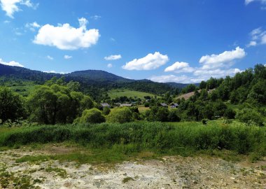 Summer mountain landscape with green hills and village houses. Carpathian Mountines, Ukraine, Eastern Europe. Clear horizon over the mountain range.