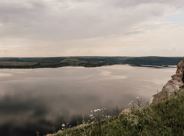 The banks of a large river. A calm smooth water view. The landscape of Bakota Bay on the Dniester river, Ukraine. High banks, green hills. Summer landscape in calm beige colors.