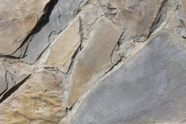 Stone wall background. Grunge close up texture. Bumpy stone surface, a fragment of an old castle wall. Detailed background in calm colors.