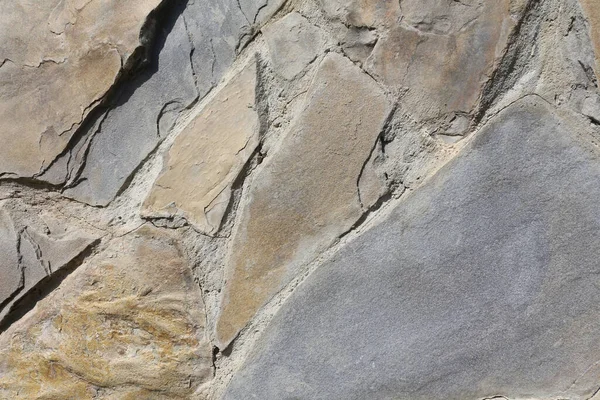 Stone wall background. Grunge close up texture. Bumpy stone surface, a fragment of an old castle wall. Detailed background in calm colors.