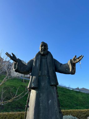 statue of Padre Pio with blue sky in the background