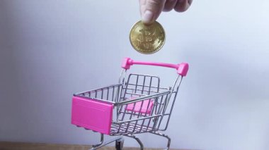 El, alışveriş vagonuna bozuk para atar.