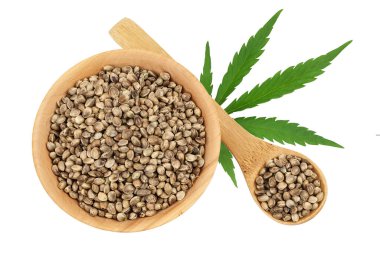 Ahşap kasedeki kenevir tohumları beyaz arka planda izole edilmiş, geniş bir alana yayılmış. Üst Manzara. Düz yatıyordu.