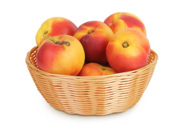 Hasır bir sepette olgun nektarin meyvesi beyaz arka planda tam derinlikte izole edilmiş..