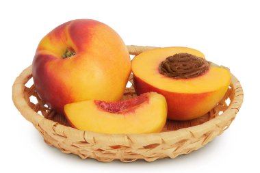 Olgun nektarin meyvesi, yarısı hasır sepette, beyaz arka planda, geniş bir alanda izole edilmiş..