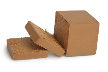 Esmer peynir. Norveç brunost 'u tam derinlikteki beyaz arka planda izole edildi.