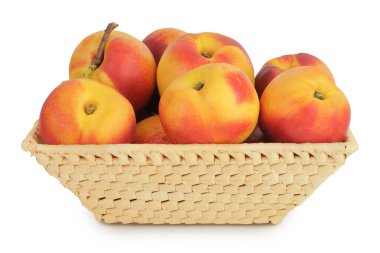 Hasır bir sepette olgun nektarin meyvesi beyaz arka planda tam derinlikte izole edilmiş..