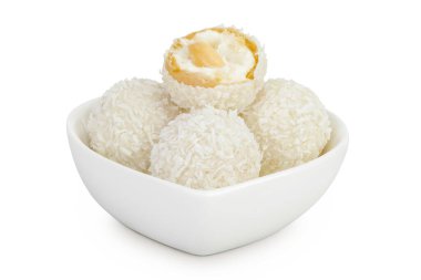 Beyaz arka planda izole edilmiş seramik kasede hindistan cevizi gevreği ve fındıklı yuvarlak raffaello..