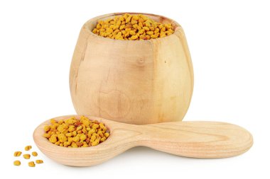 Tahta kasede polen taneleri ve beyaz arka planda izole edilmiş kaşık..