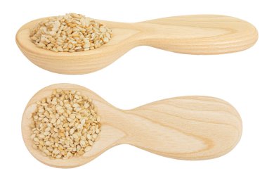 Tahta ve beyaz arka planda izole edilmiş seramik kaşıkta susam tohumları. Üst Manzara. Düz yatıyordu.