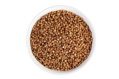 Beyaz arka planda izole edilmiş seramik kasede çiğ karabuğday. Üst Manzara. Düz yatıyordu.