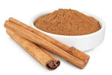 Beyaz arka planda tam derinlikte izole edilmiş seramik kasede toz bulunan tarçın çubukları..