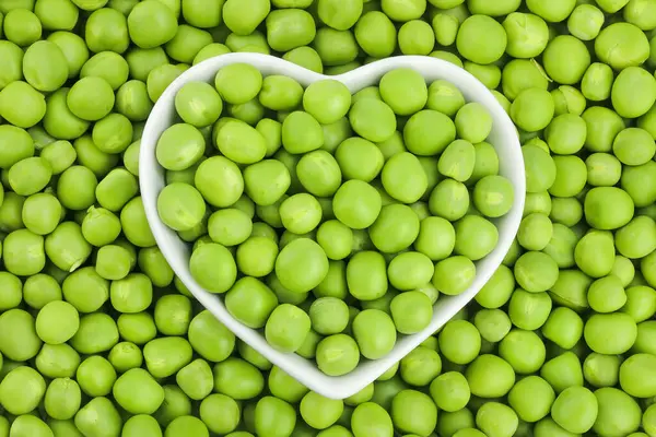 Arka plan olarak beyaz seramik kasede taze bezelyeler. Üst Manzara. Düz yatıyordu.