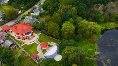 Park ağaçlarıyla çevrili şehir merkezinin dışındaki özel mülk mimarisi konutu, yukarıdan gelen hava fotoğrafçılığı