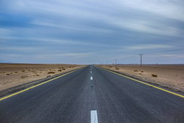 Çölde düz asfalt yolda sürmek sade basit duvar kağıdı konsepti ülkenin dramatik manzarası bulutlu hava ve kum çevresi ile