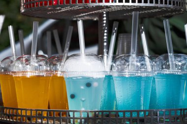 Plastik bardakta meyve kokteyli ve bar tezgahında tüp var.