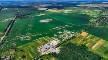 Hava aracı manzaralı yaz mevsimi banliyö çevre sahasının dışında yeşil çayır arazisinin yanındaki sanayi tesisi ahırında.