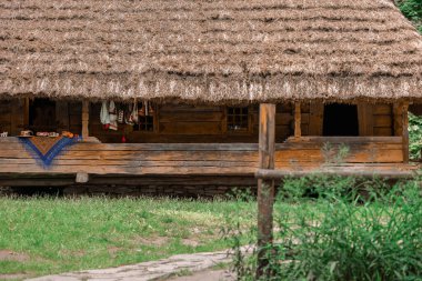 Ukrayna geleneksel ahşap evi saman ve kamış çatılı kırsal mimari ön cepheli, halk giysileri ve bahar mevsimi bahçe çiçek bahçesinde süslenmiş.