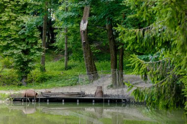 Kırsal sakin ve huzurlu orman yaz zamanı göl kıyısının çevresi ahşap küçük iskele balıkçı teknesi ve su kenarında ağ ile kaplı.