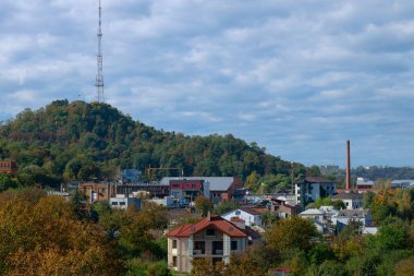 Kentin kenar mahallelerinde yeşil tepenin etrafındaki kır evleri ve TV kulesi altyapısı Avrupa köyü çevresi