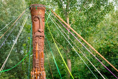 Bahar Pagan bayramı şenlik etkinliği ahşap oyulmuş putların sütunları renkli kurdeleler doğa orman Nisan ortamı