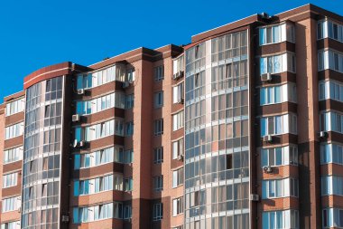 Çok katlı yüksek katlı bir apartman, mavi gökyüzü olan bir yerleşim bölgesi.