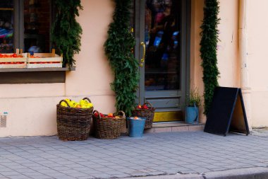 Kaldırımın kenarındaki meyva tezgahında sebzeler satılıyor. Şehir manzarası, dükkan girişi, dış görünüş, şehir manzarası.