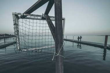 Deniz kıyısında ahşap iskele, suda gün batımı.