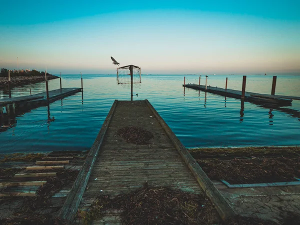Deniz kıyısında ahşap iskele, suda gün batımı.