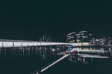 Geceleyin su üzerindeki yaya köprüsünü aydınlattı.