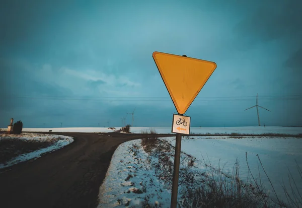 yellow road sign at crossroads in winter