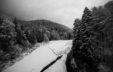 Dağlardaki karla kaplı ormanın arasındaki donmuş nehir.