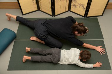 Kafkasyalı osteopat ofisinde genç bir çocukla esneme hareketleri yapıyor.