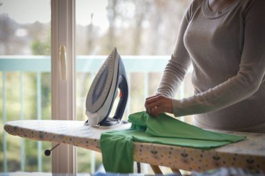 Yaşlı insanlar için evde ütü yapan melez bir kadın.