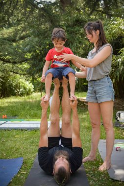 Genç bir çocuk bahçede koçlarıyla denge egzersizi yapıyor.