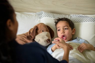 Hasta çocuk yatakta yatıp ilaç alıyor.