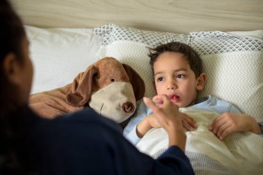 Hasta çocuk yatakta yatıp ilaç alıyor.
